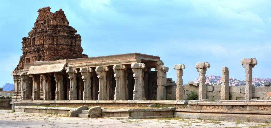 Ancient carved stone temple pillars and mandapa of Bharat overlooking sacred landscape